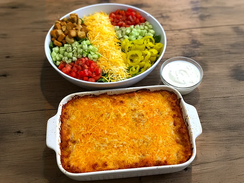 Baked spaghetti pan with a large salad bowl and ranch